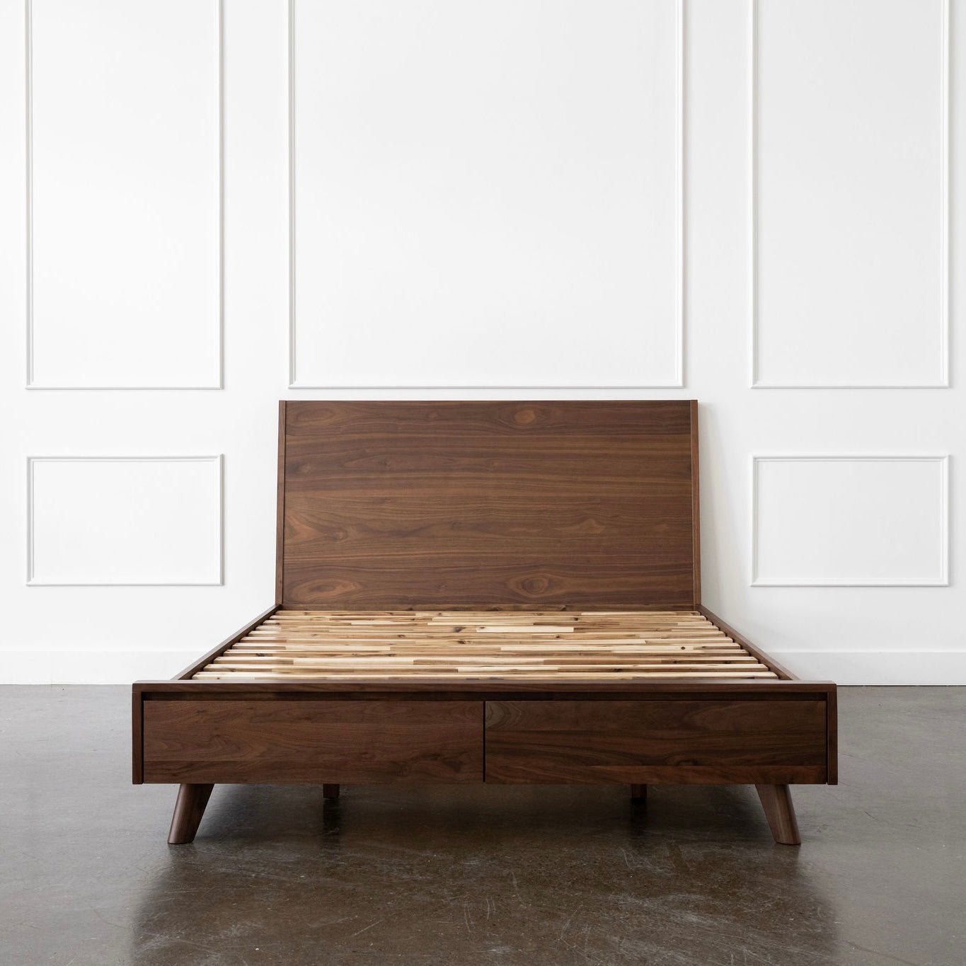 Walnut bed with slatted design against a white paneled wall