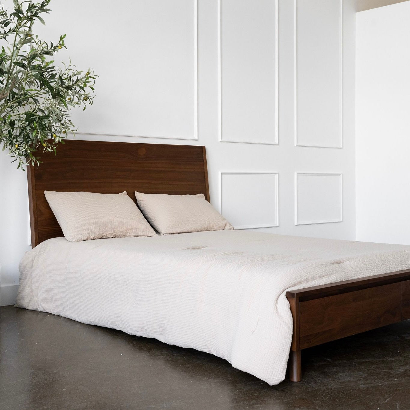 Wooden bed with white bedding in a minimalistic room.