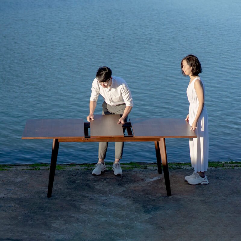 Two people extending an extendable walnut dining table